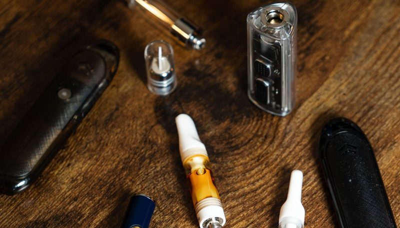 มือกำลังใช้ cotton swab จุ่มแอลกอฮอล์ isopropyl ทำความสะอาด Chamber ภายในของ Vaporizer สีเงิน มีขวดแอลกอฮอล์และผ้าไมโครไฟเบอร์วางข้างๆ บนพื้นผิวสีขาวสะอาด